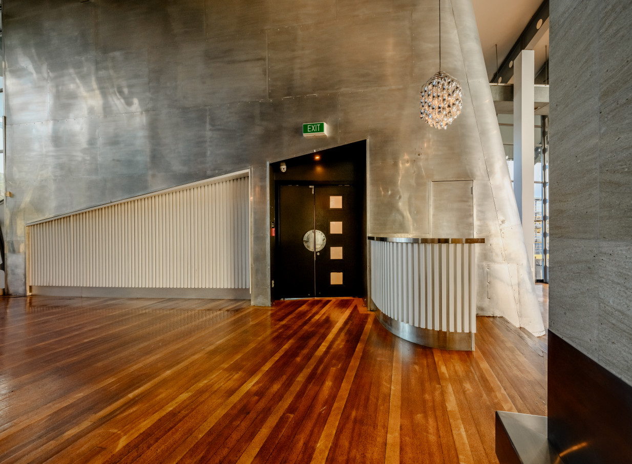 Inside Mechanics Bay, Auckland, a modern event space with striking metallic walls and polished hardwood floors.