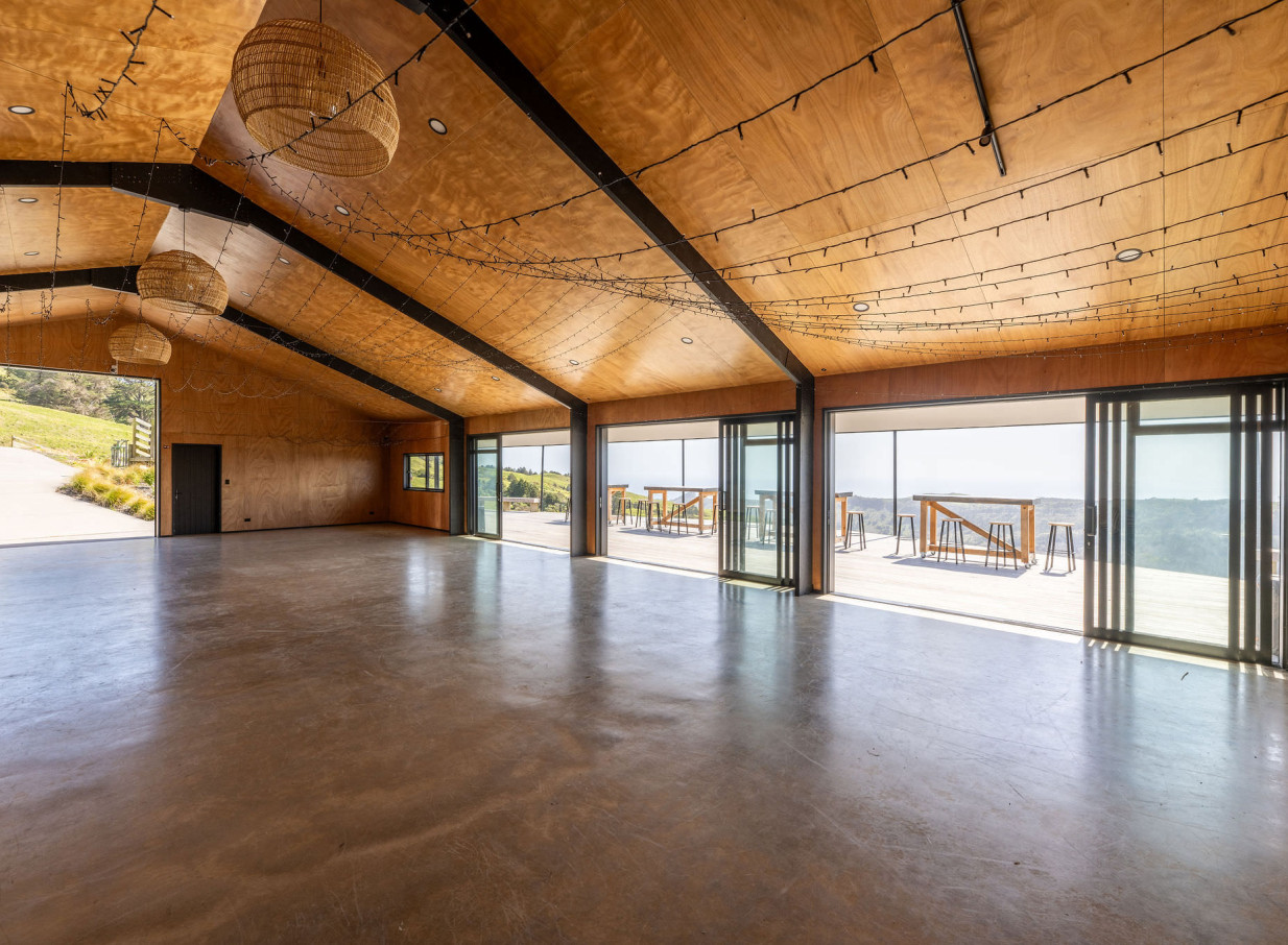 The Black Barn at Vanderosa Farms in Auckland is a rustic-modern event space featuring a high wooden ceiling and panoramic deck views.
