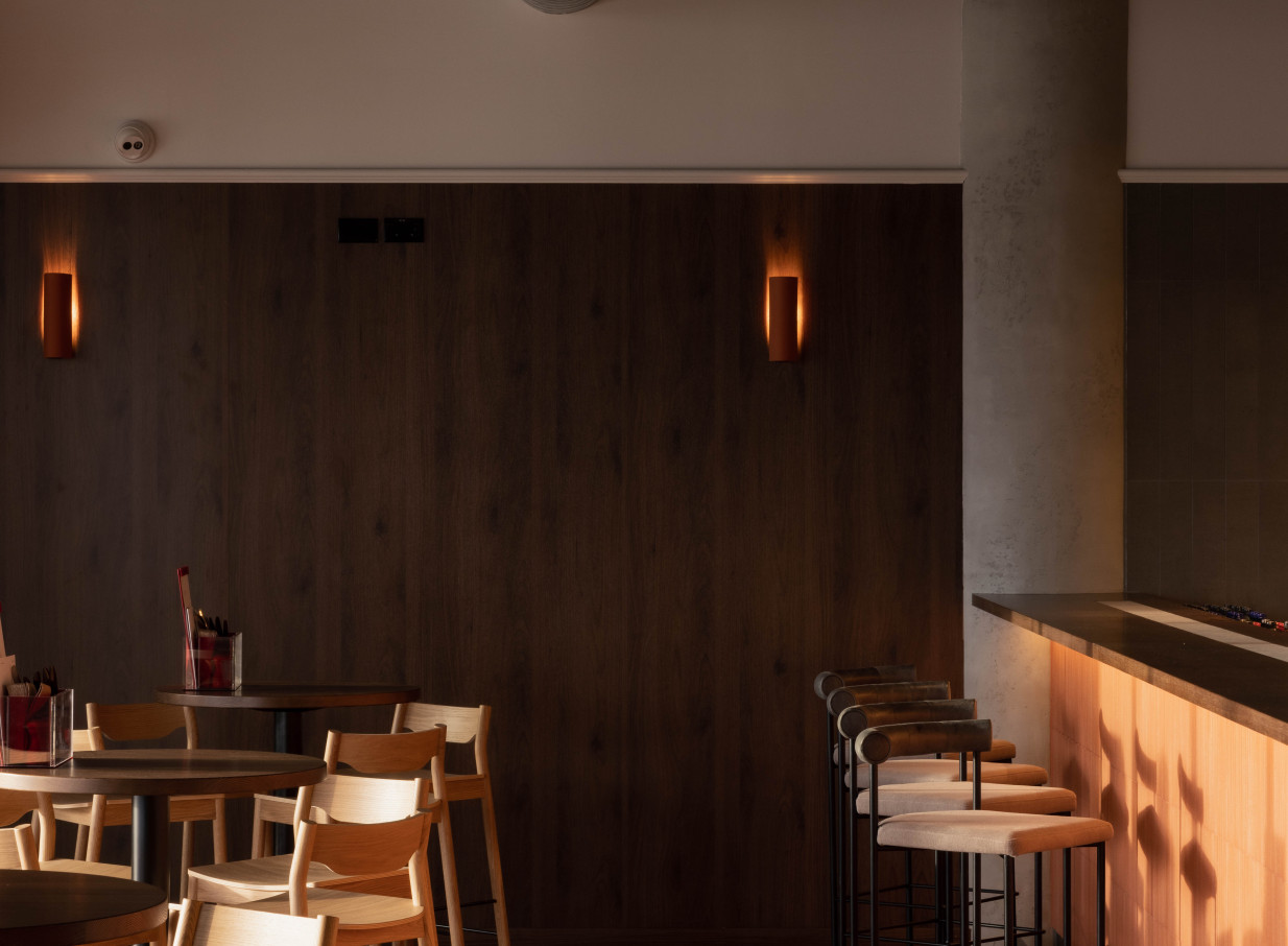 A modern bar area within Somm Auckland, showcasing warm lighting, natural timber walls, and comfortable seating for a chic wine experience.