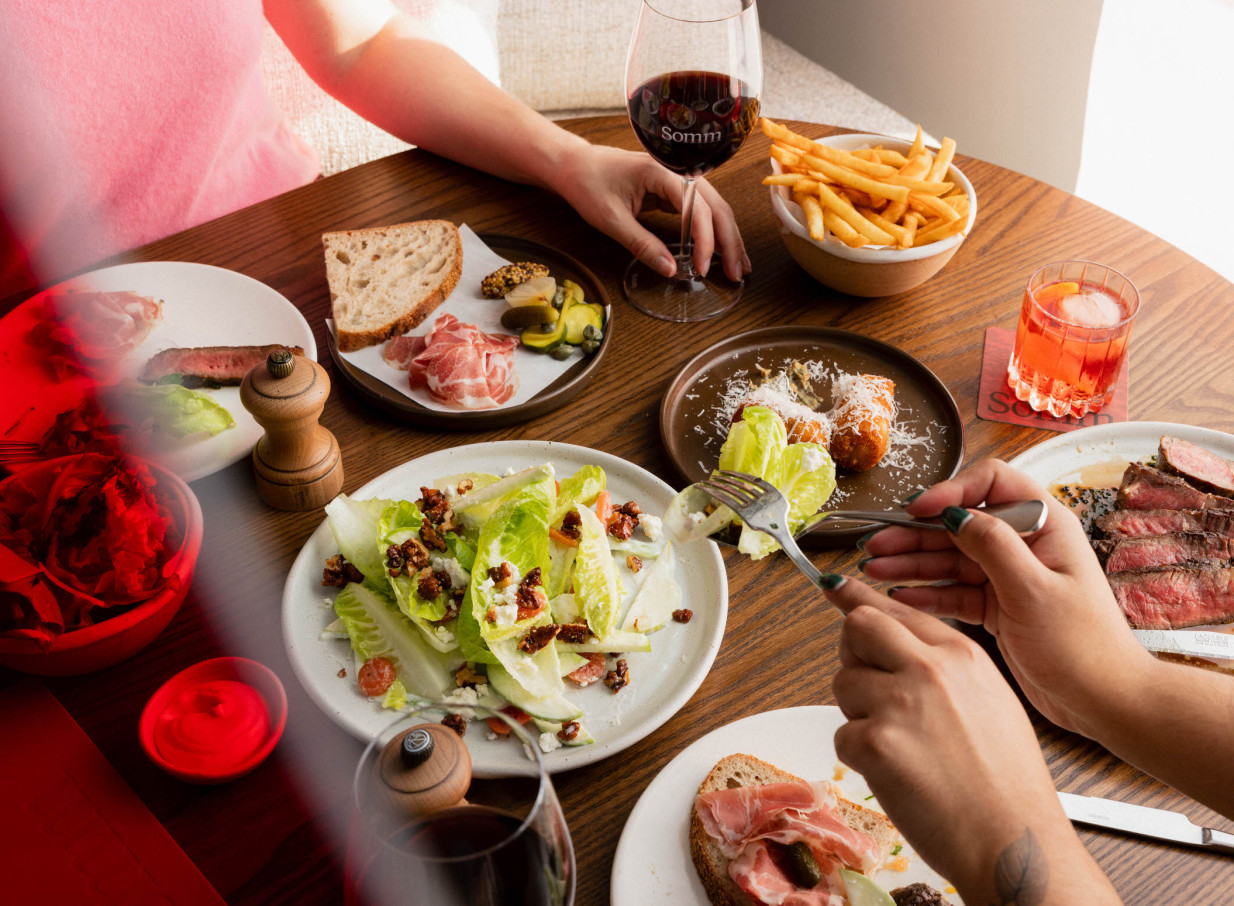 A chic shared dining experience with wine and diverse plates at Somm, Auckland, reflecting its modern, winery-inspired design.