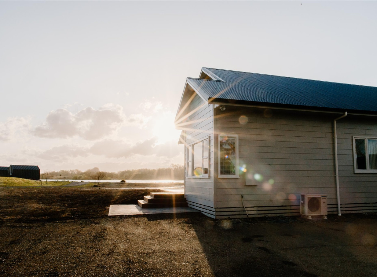 A contemporary-style cabin at Backpaddock Lakes in Hawke's Bay, offering lakeside accommodation bathed in bright, warm sunlight.