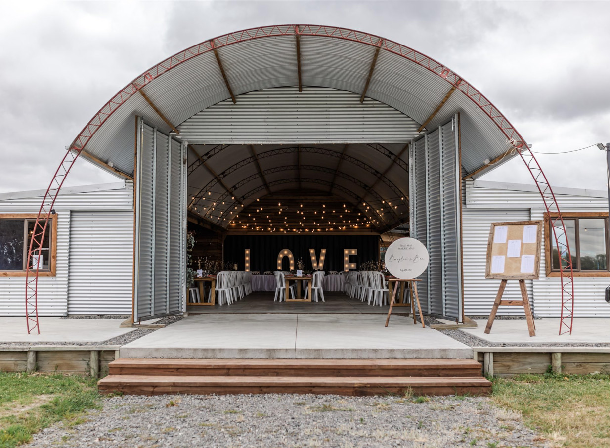 The rustic corrugated iron barn at Backpaddock Lakes, Hawke's Bay, hosts a lit reception with "LOVE" letters.