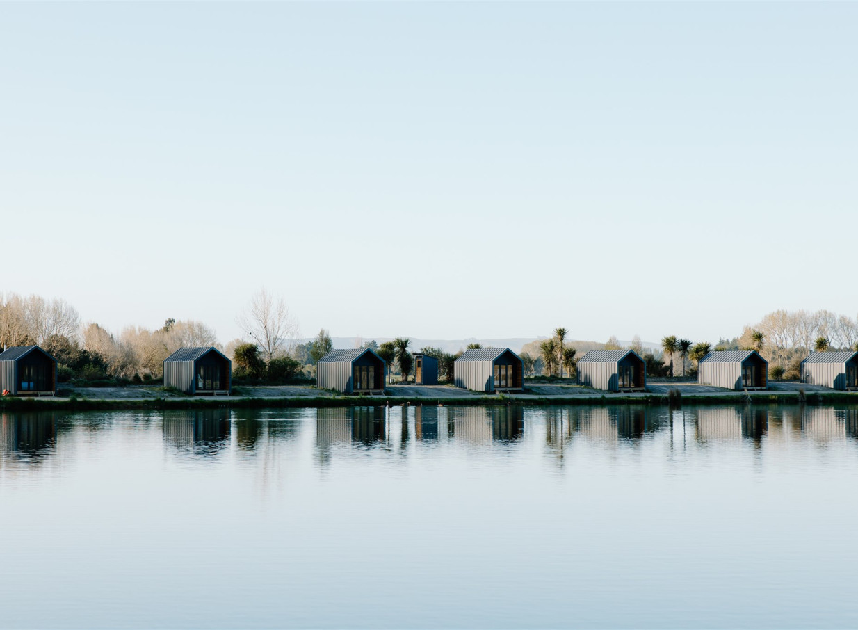 A row of contemporary lakeside cabins at Backpaddock Lakes in Hawke's Bay, providing unique accommodation options.