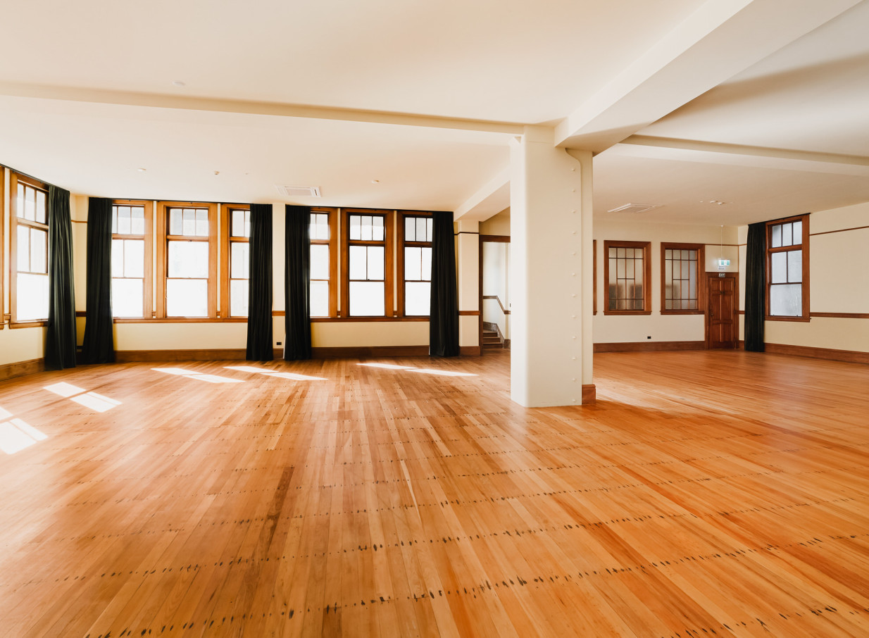The bright grand ballroom at Erskine Chapel, Wellington, features polished wooden floors and large windows.