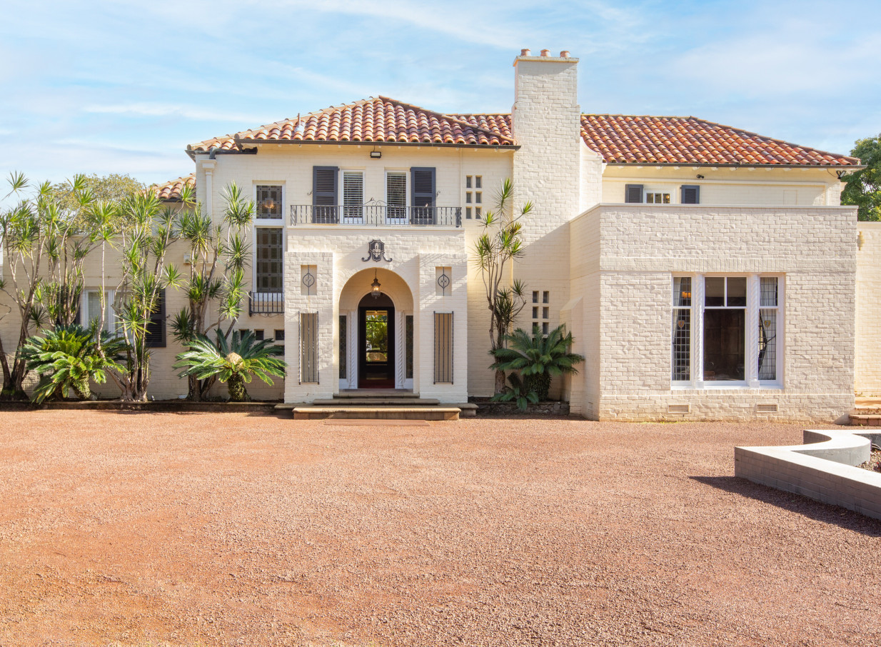 The Spanish-style entrance of Puketutu Island Estate in Auckland, featuring an arched doorway and terracotta roof.
