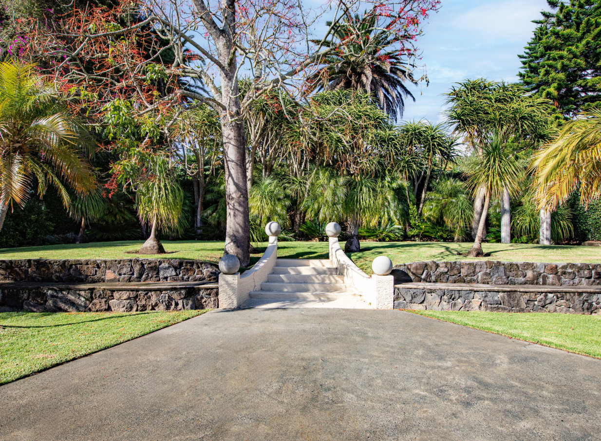 A lush garden pathway with ornate stone steps at the Spanish Mission-style Puketutu Island Estate in Auckland.
