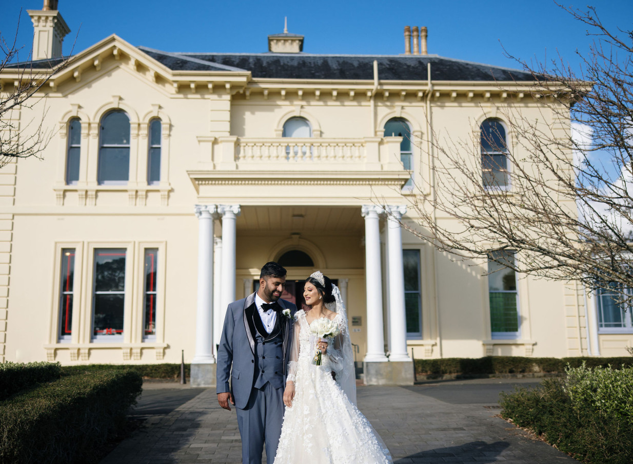 A wedding couple enjoys an outdoor moment at The Arts House Trust at Pah Homestead, an Italianate-inspired venue in Auckland.