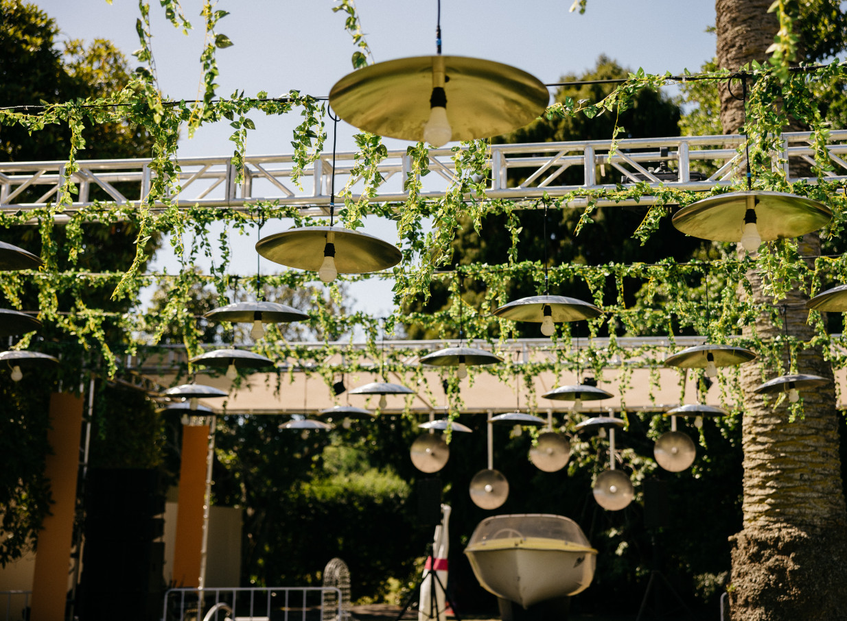 An outdoor event space at the Italianate Arts House Trust at Pah Homestead, Auckland, adorned with overhead lights and green vines.