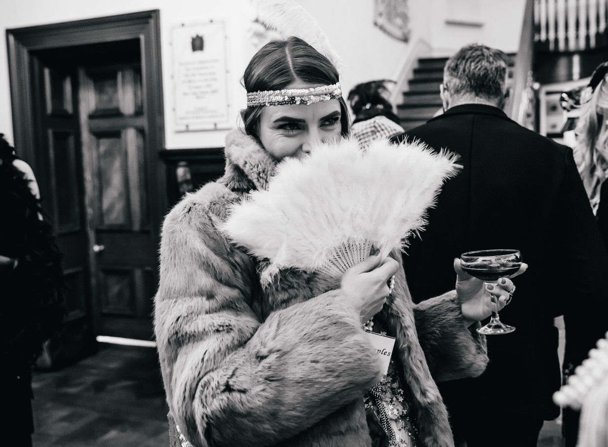 A woman in a 1920s-inspired fur coat and feather fan enjoys a themed event inside the Italianate Pah Homestead in Auckland.