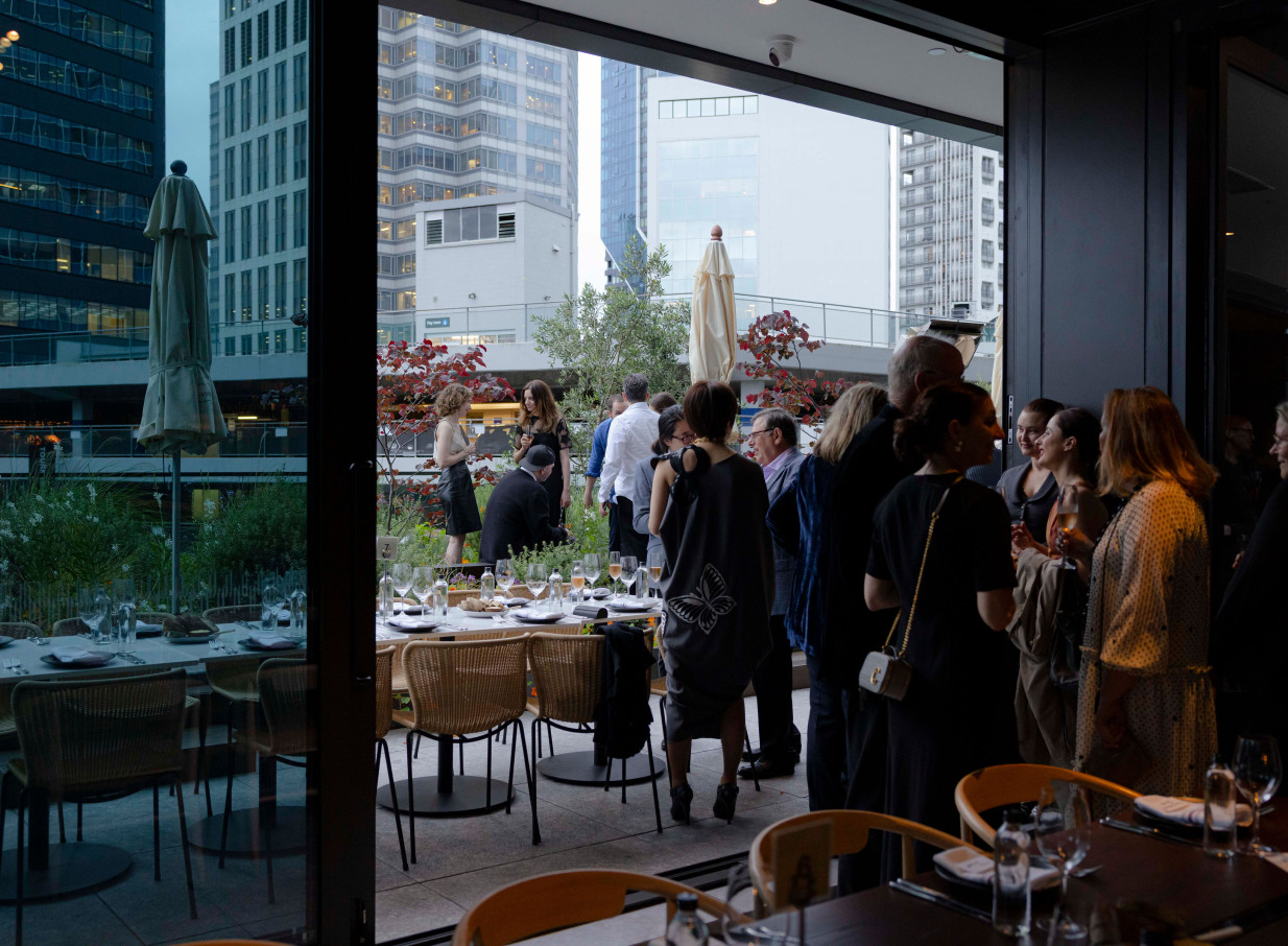 Guests mingle at a sophisticated indoor-outdoor event on Onslow's modern garden terrace in Auckland, featuring a city view.