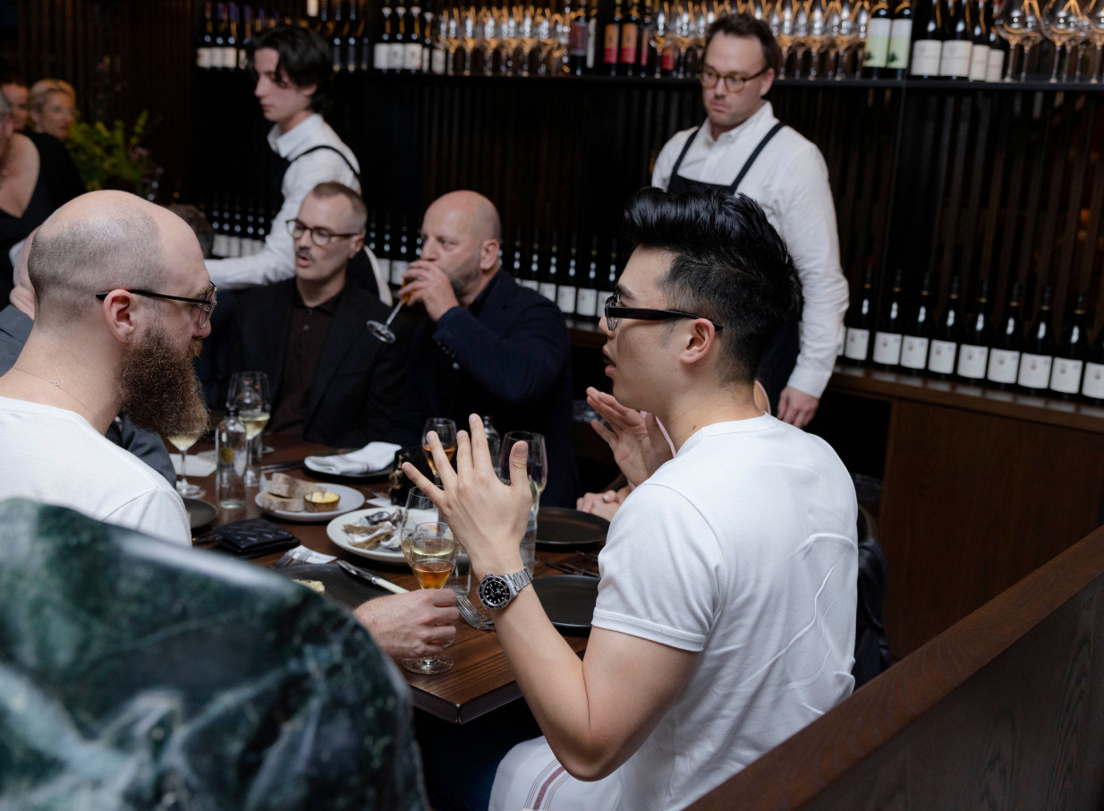 Guests enjoy a lively dinner in Onslow Auckland's sophisticated, dark oak-led dining room.