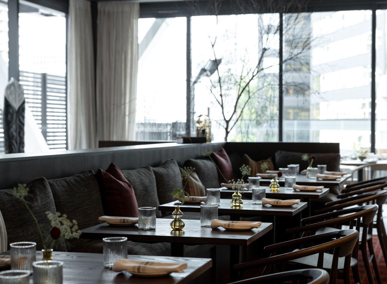 Onslow in Auckland offers a sophisticated and modern dining room interior with dark oak details, comfortable banquettes, and city views.