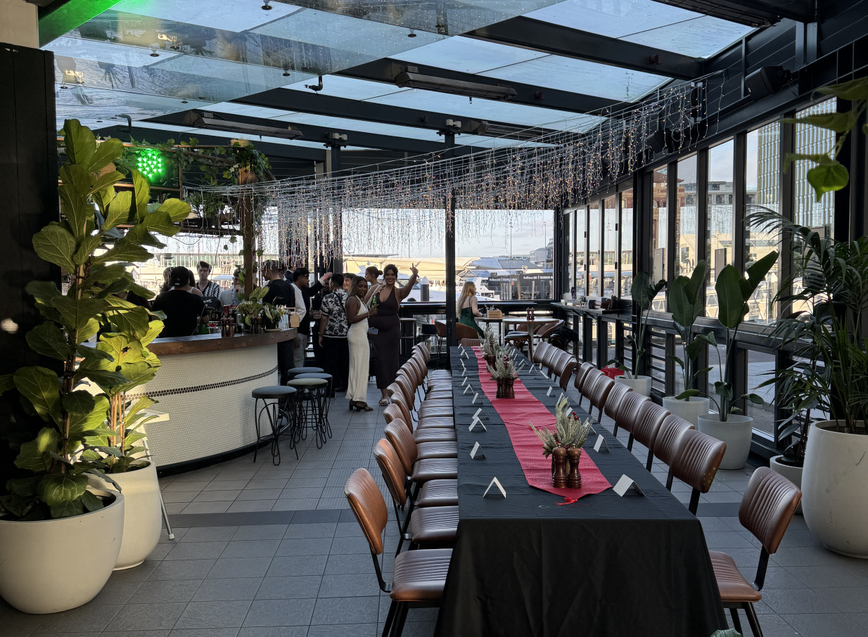 An elegant modern dining and bar area at Wharfside Function Centre, Auckland, blending indoor and outdoor space with waterfront views.