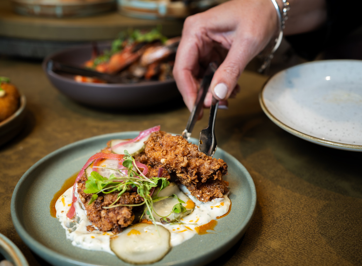 A hand serves crispy fried chicken, a small plate from the luxurious, Gatsbyesque 1851 Social Bar in Christchurch.