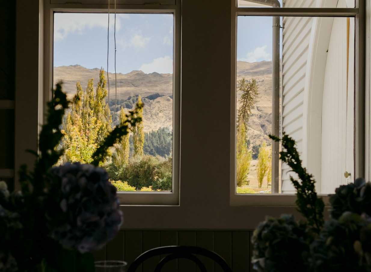 A scenic mountain view through bright windows inside the lovingly restored historic Waikākā Church, Queenstown.