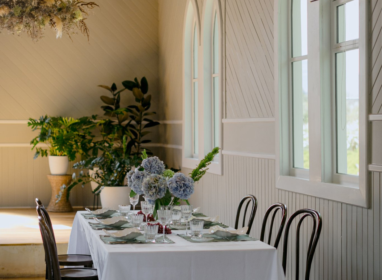 An elegant dining setup within the bright, historic chapel interior of Waikākā Church, a charming event venue in Queenstown.