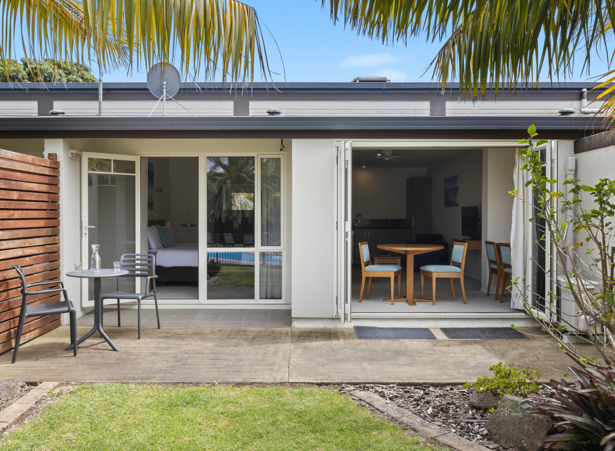 An outdoor patio connects to a modern resort-style studio at Taipa Beach Resort in Northland.