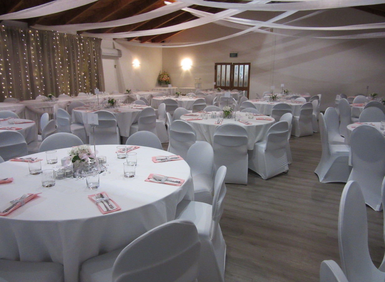 An elegant banquet room at Taipa Beach Resort in Northland, with draped fabric, wooden ceiling beams, and sparkling fairy lights.