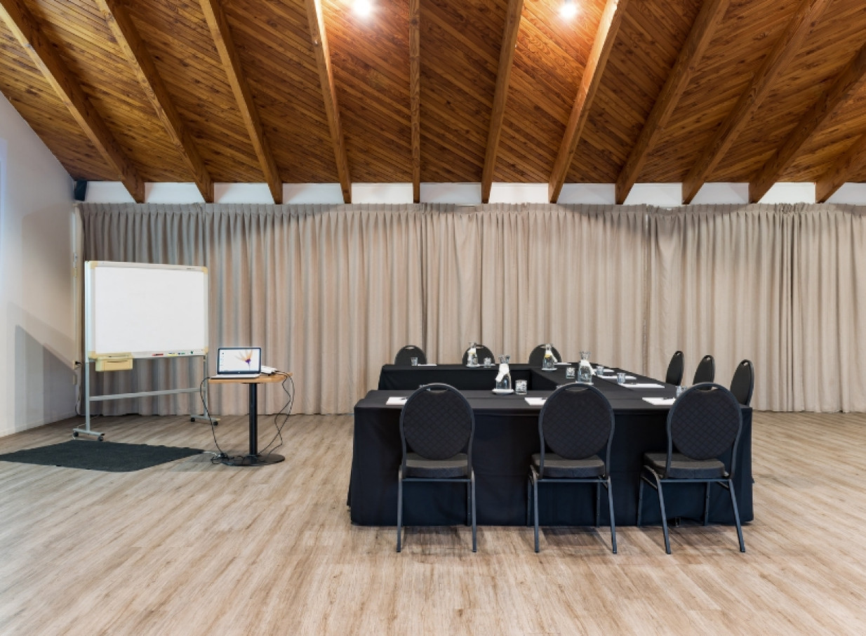 This conference room, featuring a warm, beamed ceiling, is set up for a meeting at Taipa Beach Resort, Northland.