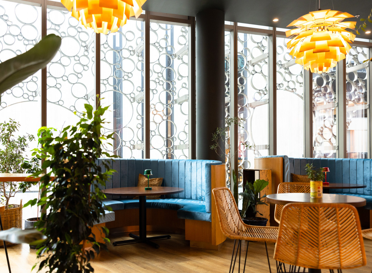 Bar Franco's modern Italian dining area in Christchurch features luxe blue booths, rattan chairs, and decorative circular window screens.