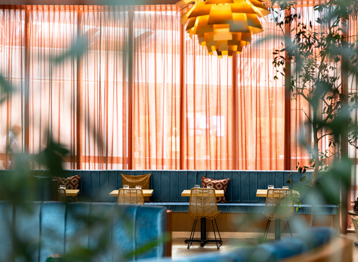 An inviting modern Italian dining room at Bar Franco in Christchurch, featuring plush velvet booths and warm amber drapes.