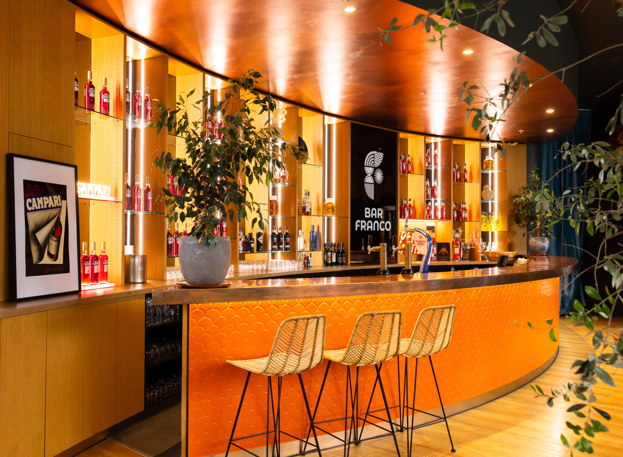 The vibrant, retro-Italian bar at Bar Franco in Christchurch, with its curved orange counter and illuminated shelving.