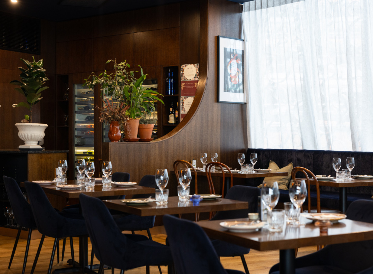 The elegant Italian dining room at Bar Franco in Christchurch, with dark wood, velvet seating, and set tables.