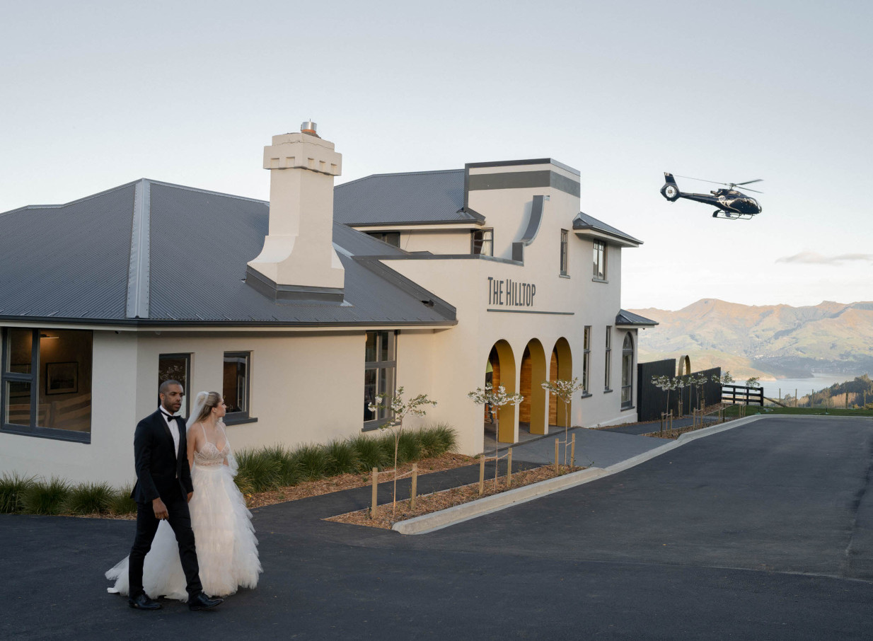 A wedding couple outside The Hilltop, a modern-elegant Christchurch venue boasting scenic views and helicopter access.