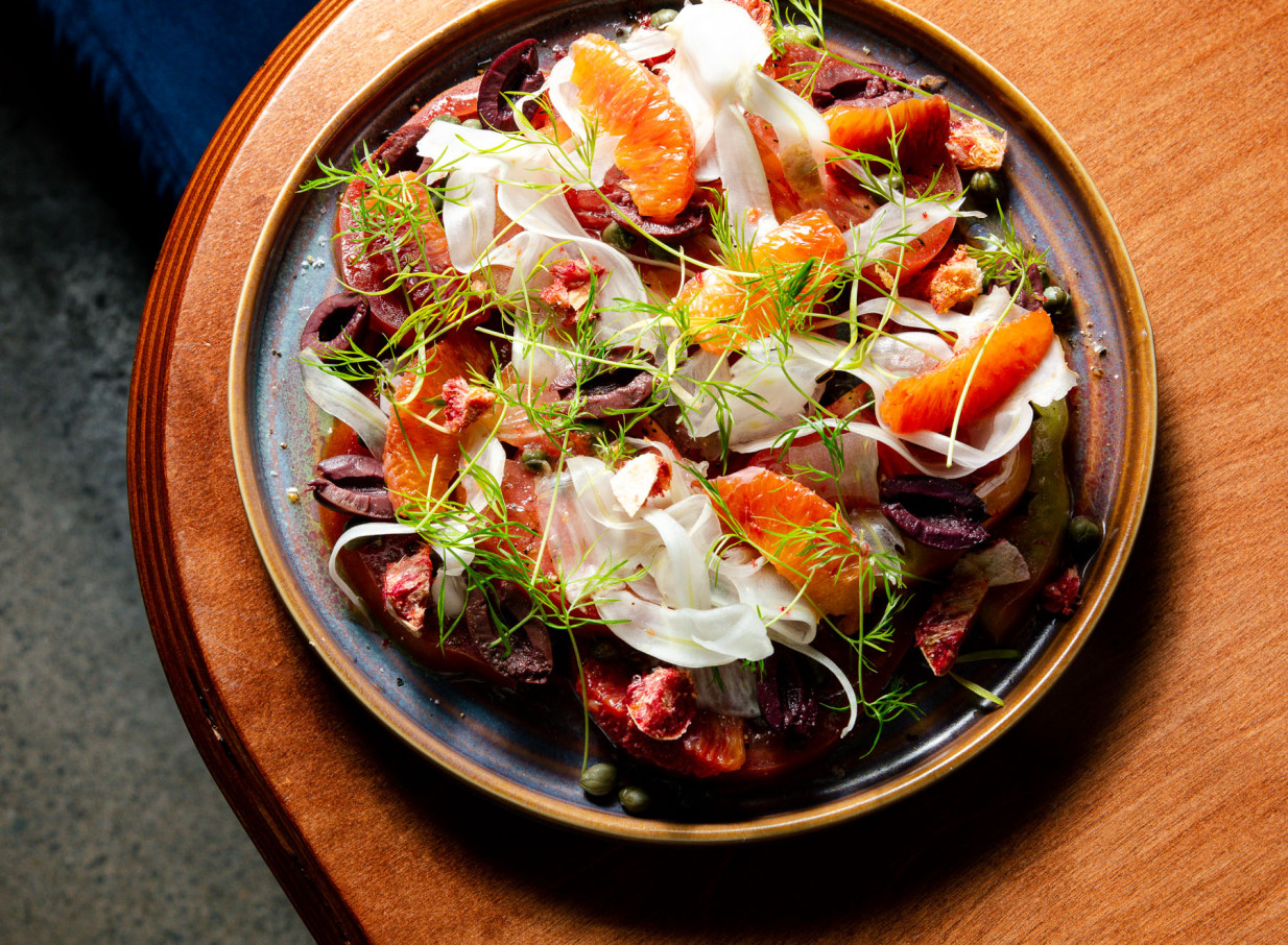 A vibrant citrus and olive salad, artfully prepared, reflecting the modern elegance of The Hilltop x 5th Street in Christchurch.