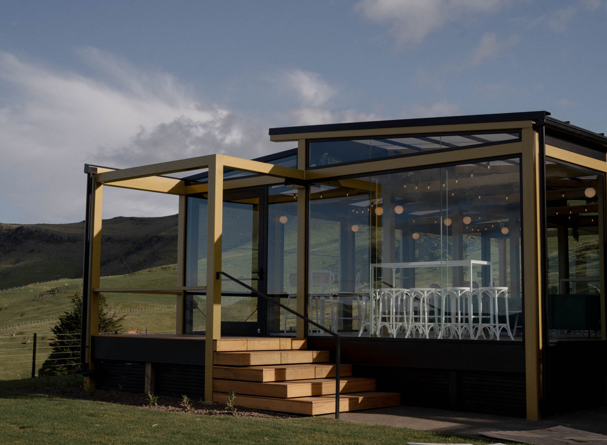 The Hilltop in Christchurch features a modern glass-enclosed event space with panoramic views of rolling hills.