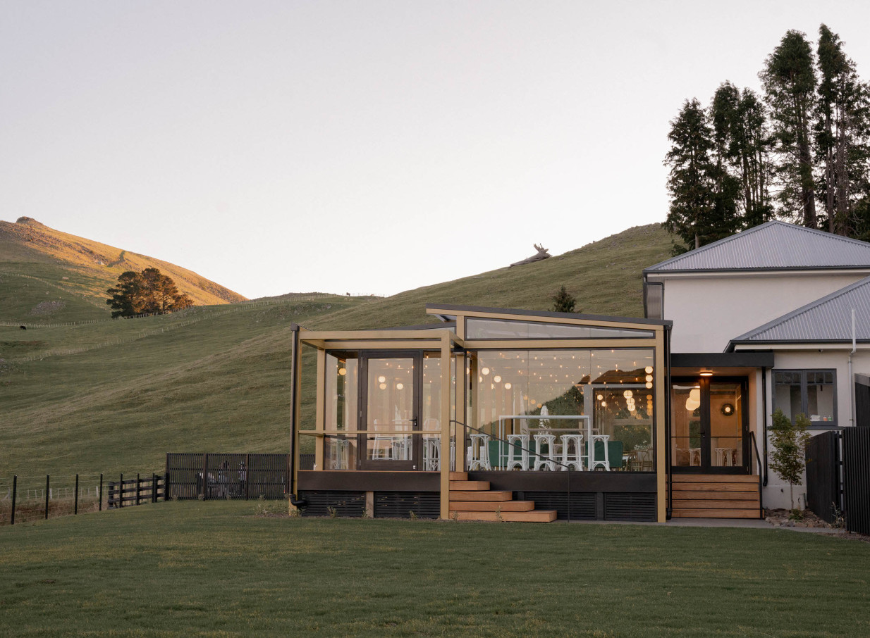 The Hilltop in Christchurch features a modern, glass-enclosed event space with sweeping views of the surrounding green hills.