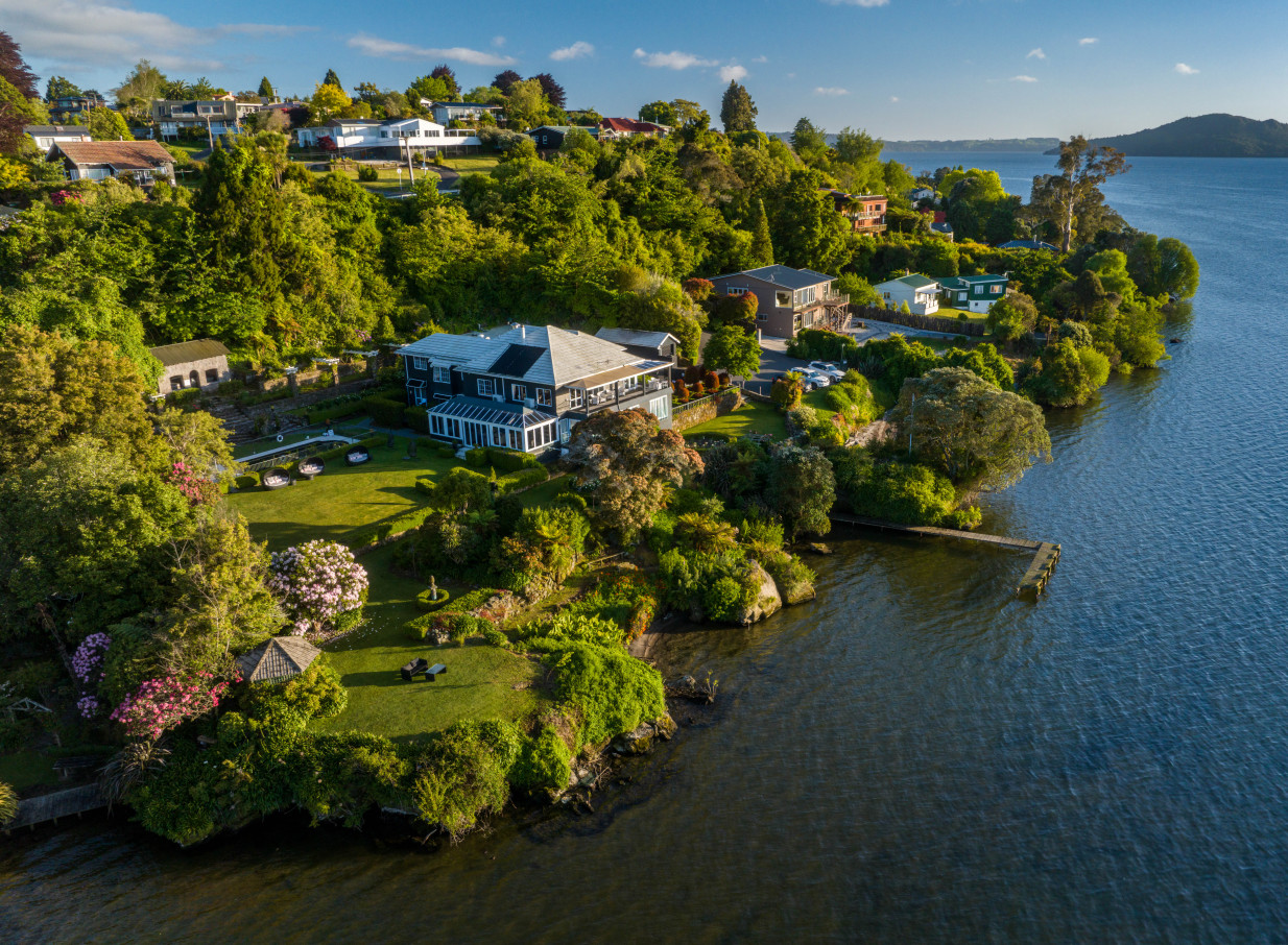 Aerial view of Black Swan Lakeside Boutique Hotel in Rotorua, an elegant lakefront property with sweeping lawns and a private jetty.