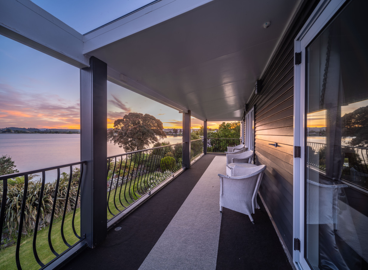 A covered balcony at the Black Swan Lakeside Boutique Hotel in Rotorua offers a luxurious sunset view over the lake.