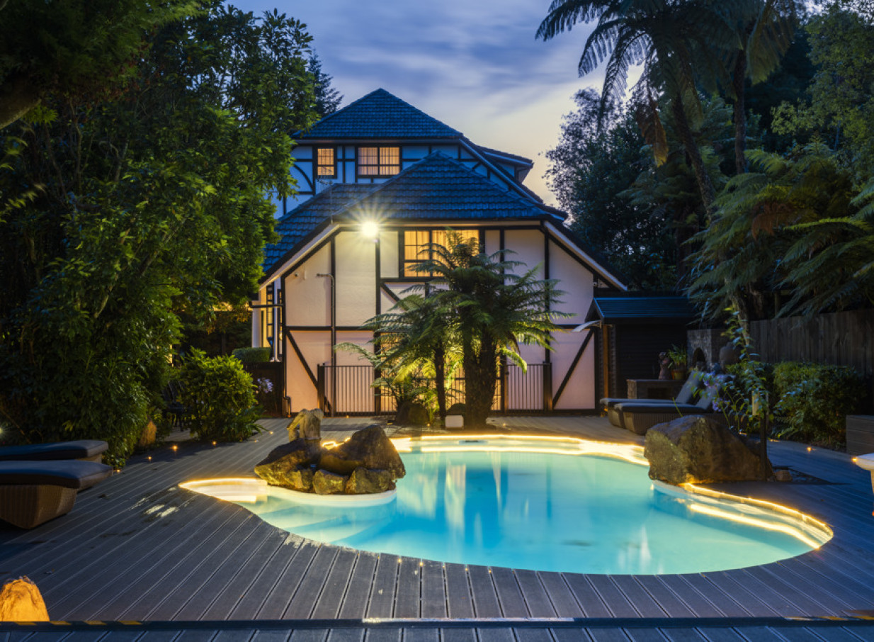 Hana Lodge Rotorua's Tudor-style lodge frames a beautifully lit outdoor swimming pool.