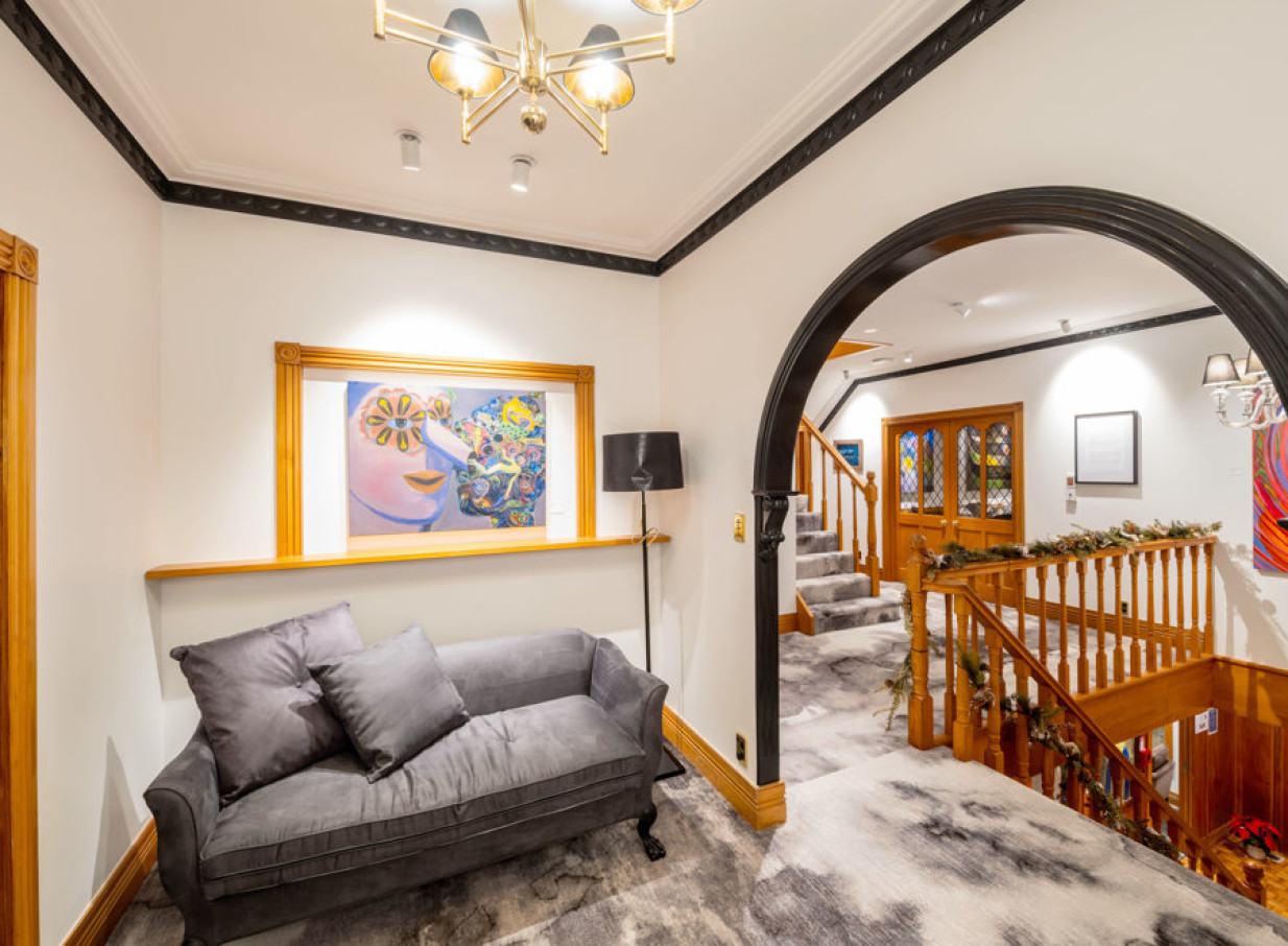 An elegant lounge and staircase with dark wood details and vibrant art characterize the interior of Hana Lodge, Rotorua.