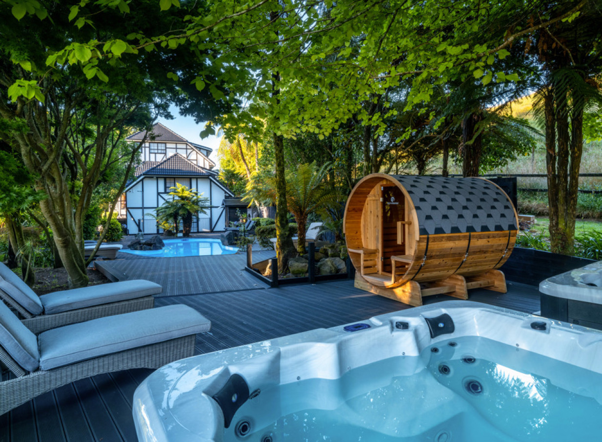 An outdoor spa area with a hot tub, barrel sauna, and pool at the elegant Hana Lodge in Rotorua.