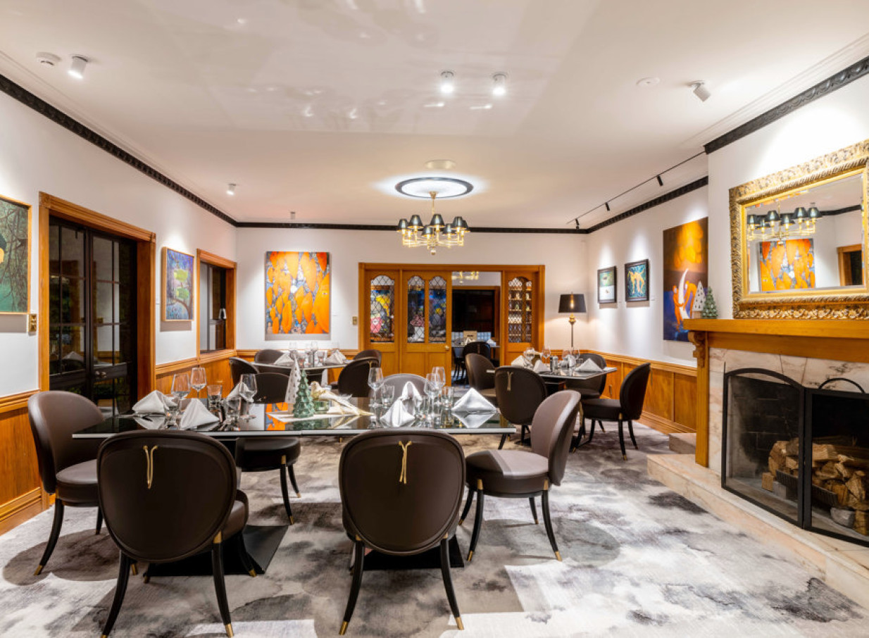 Hana Lodge's elegant, art-filled dining room in Rotorua, featuring modern furnishings and a warm fireplace.