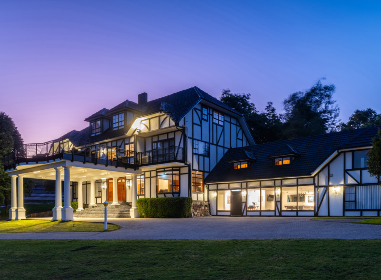 The elegant, half-timbered Hana Lodge in Rotorua glows at dusk, showcasing its illuminated grand entrance.
