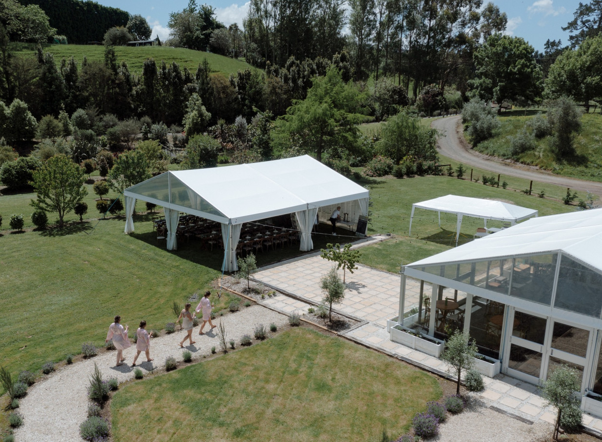 Guests walk by white event marquees at Villa Vie, a French-inspired estate with manicured gardens in Bay of Plenty.