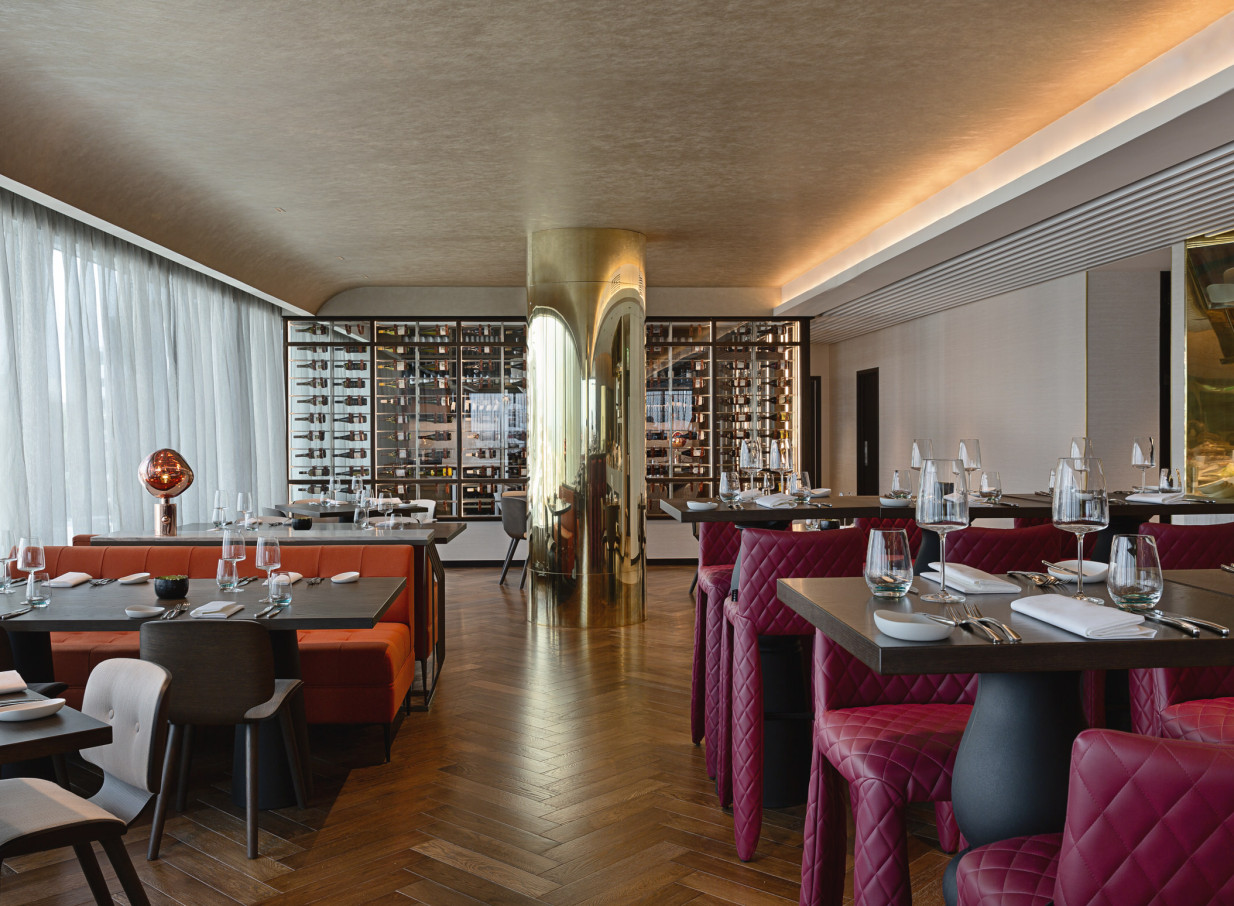 The modern, avant-garde dining room with gold accents and a wine wall at SO/ Auckland offers a luxurious experience.