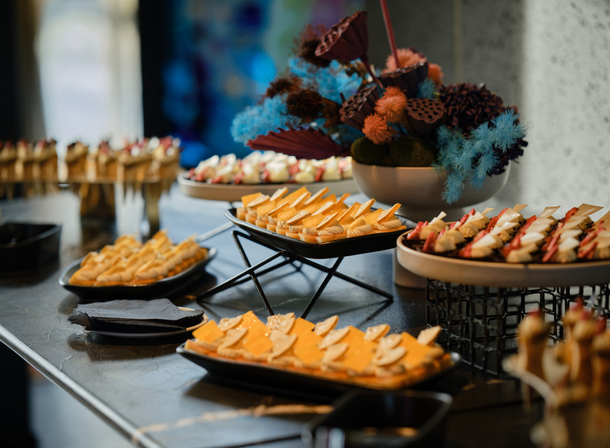 A sophisticated food display with diverse desserts is presented on a dark, sleek counter at the bold, avant-garde SO/ Auckland.