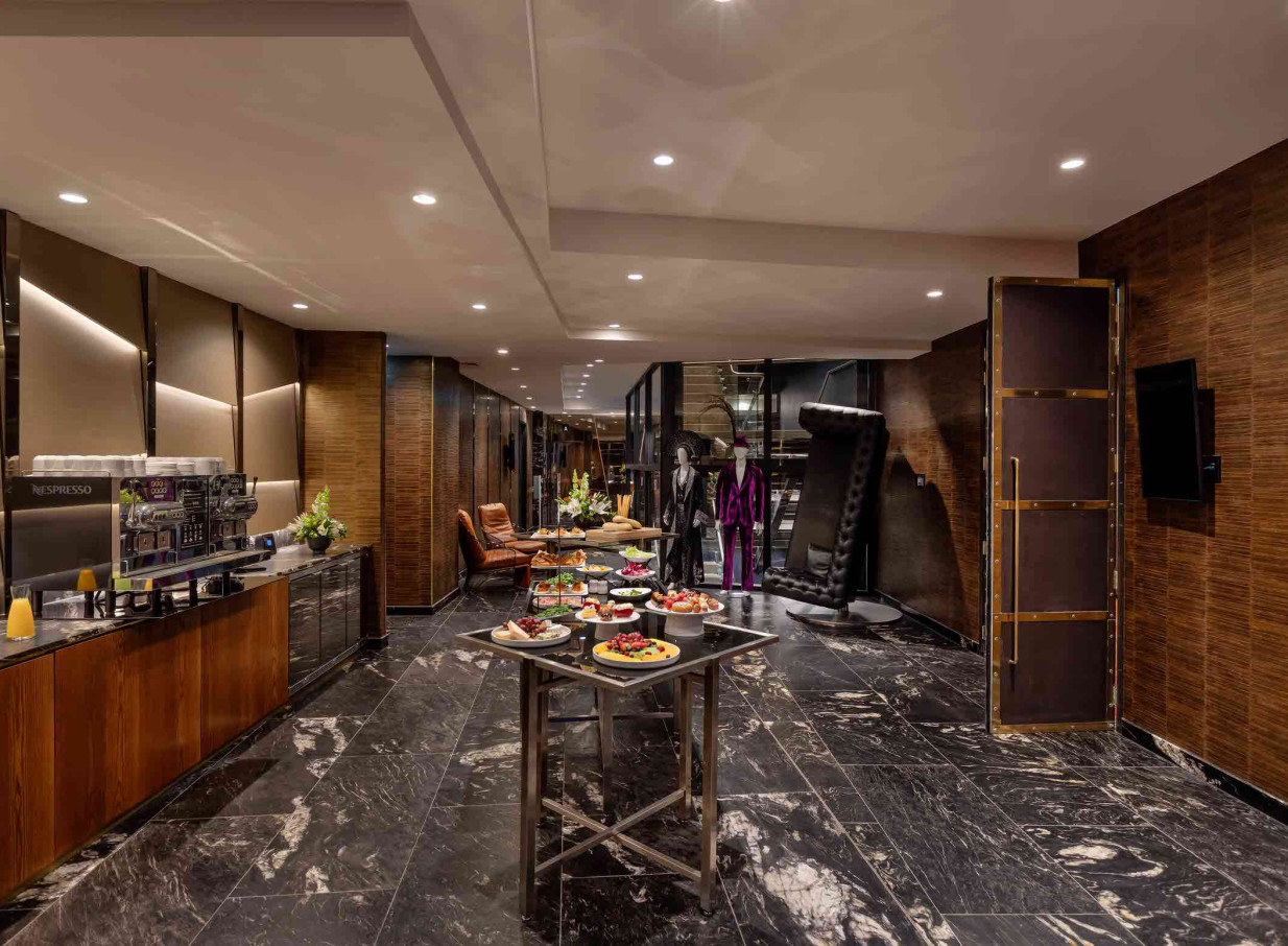 A stylish buffet in the bold, avant-garde lobby of SO/ Auckland, featuring dark marble floors and unique decor.