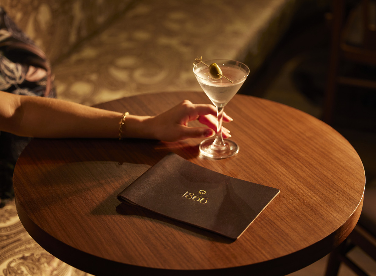 A patron enjoying a martini in the plush, prohibition-era 1866 Speakeasy Bar at The Clements Hotel, Waikato.