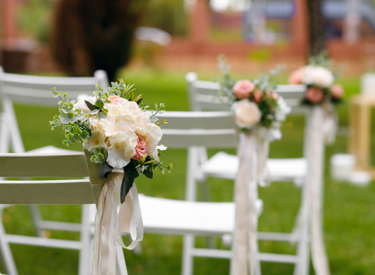 Elegant outdoor ceremony chairs with floral decorations on the events lawn of the historic Beaux-Arts Clements Hotel in Waikato.