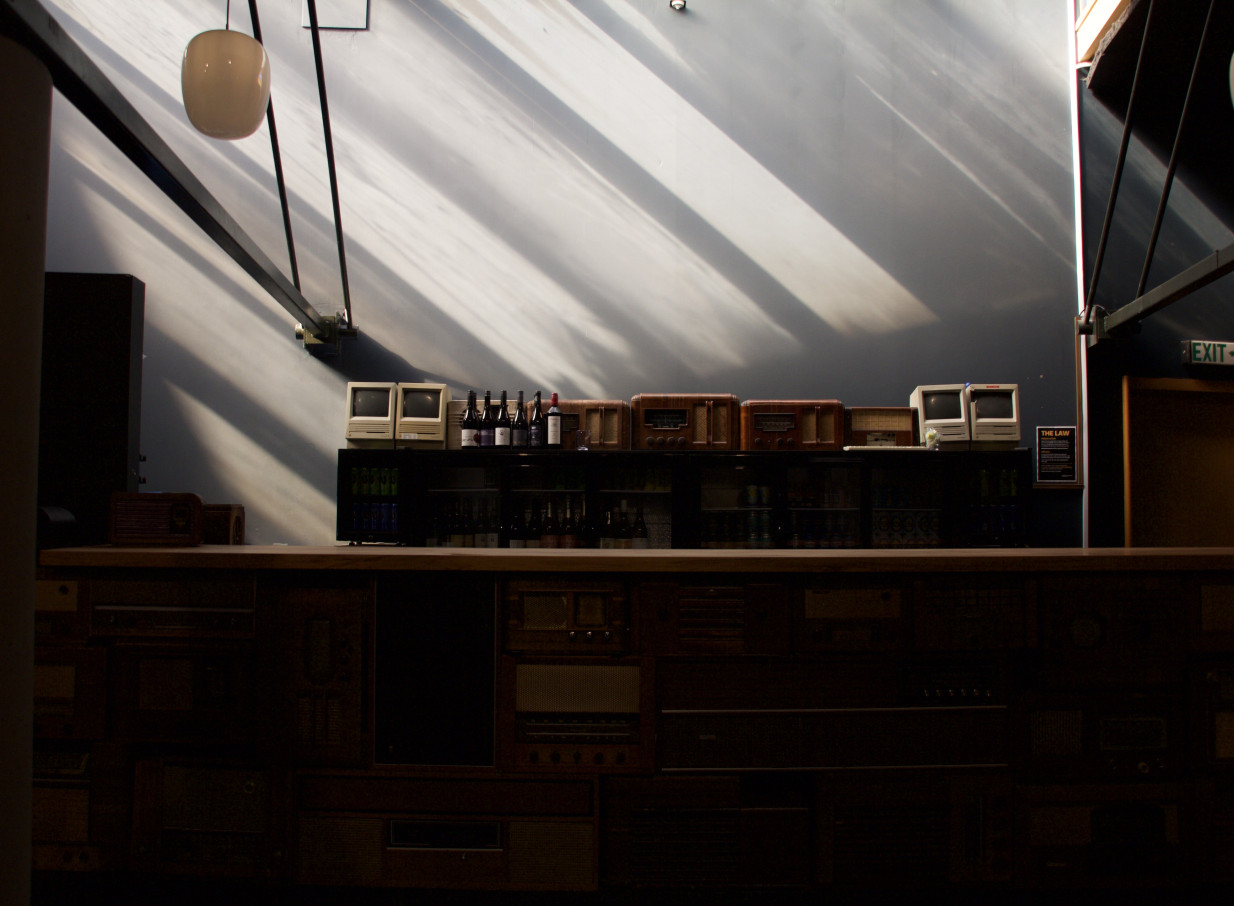 The eclectic bar at Meow Nui, Wellington, showcases vintage electronics under dramatic lighting in its architecturally stunning space.