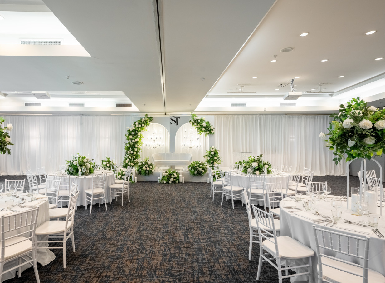 An elegant, contemporary banquet setup at Novotel Auckland Ellerslie, adorned with white and green floral decor.