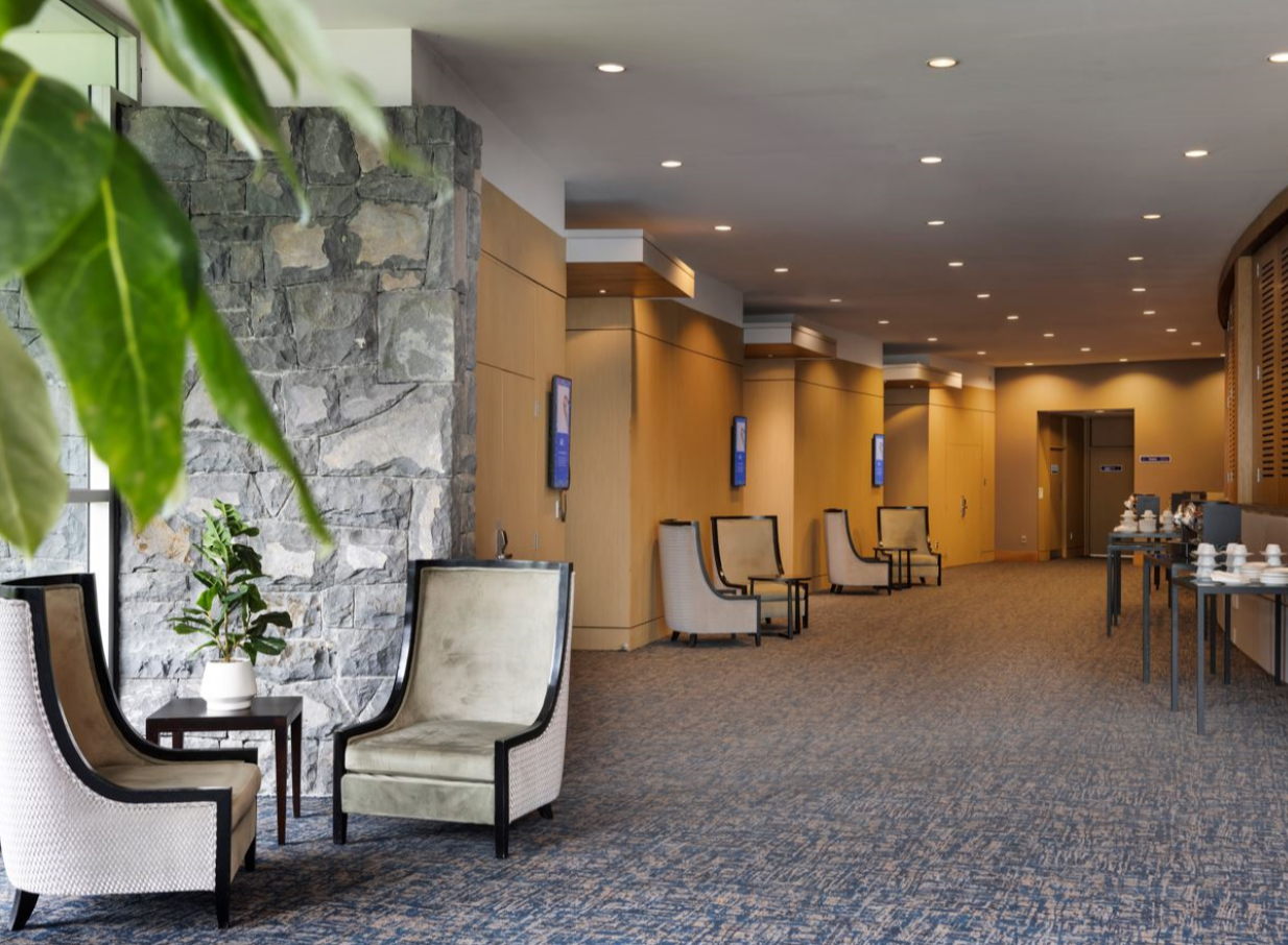 A contemporary lounge at Novotel Auckland Ellerslie, Auckland, with elegant seating and a natural stone pillar.