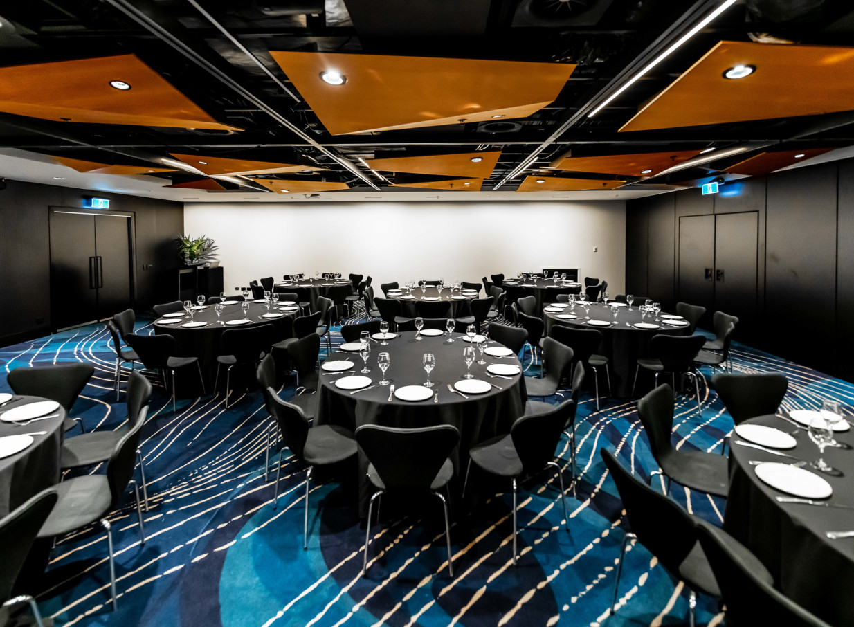 A modern banquet setup fills a flexible event room at Auckland's Aotea Centre, featuring a distinctive patterned carpet and geometric ceiling.