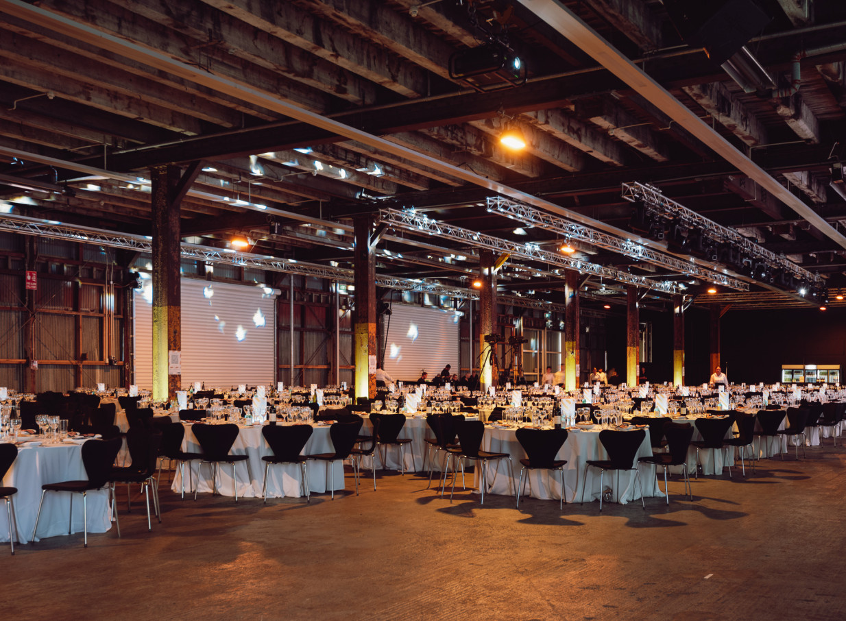 A gala dinner setup fills the industrial-chic event space of the heritage-listed Shed 10 in Auckland.