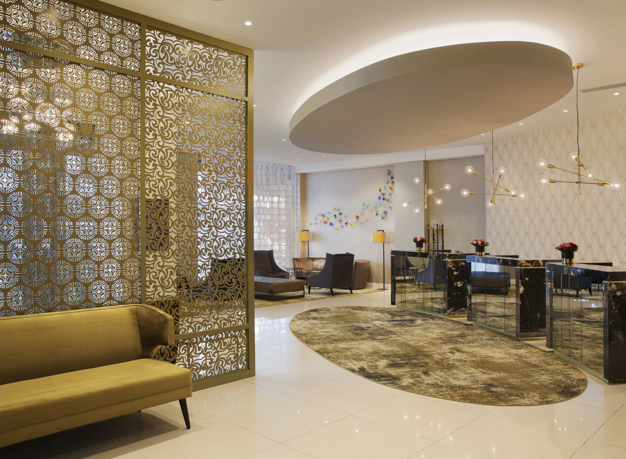 Mövenpick Hotel Auckland's contemporary chic hotel lobby features ornate screens, plush seating, and modern lighting.